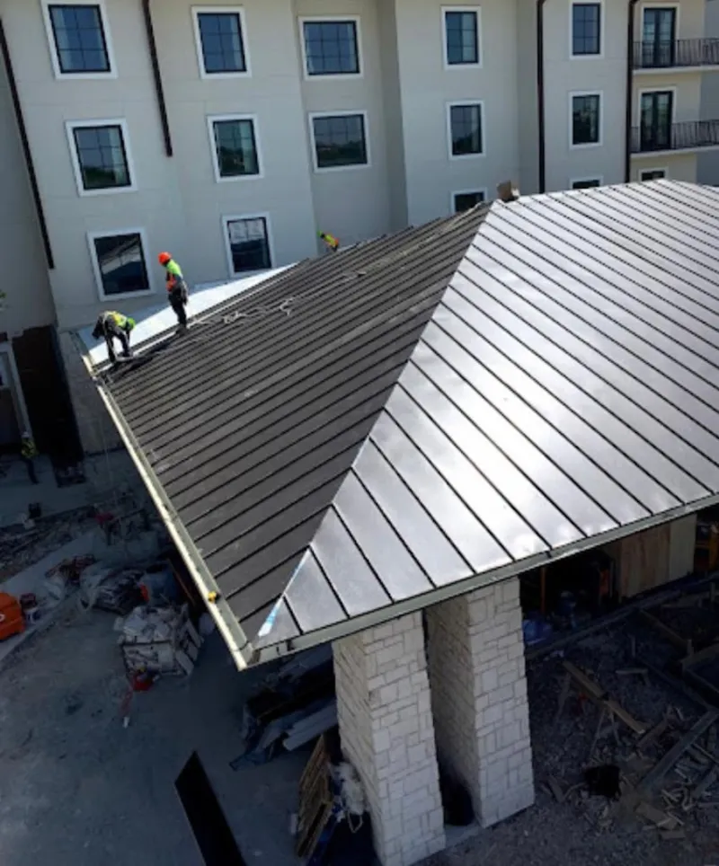 Crew installing standing seam metal roof panels on a commercial project in Leisure World